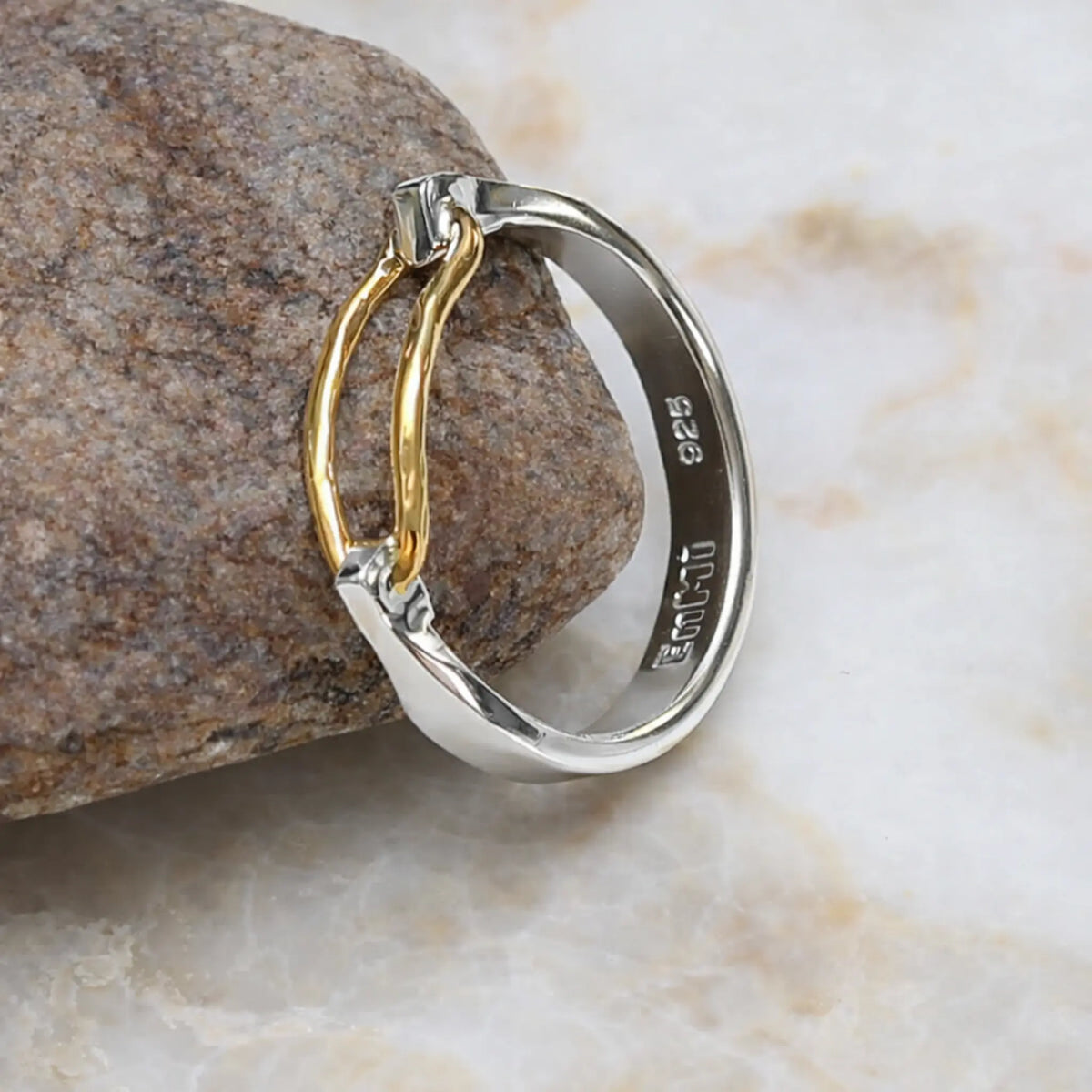 Two-toned ring with gold and silver on a stone surface