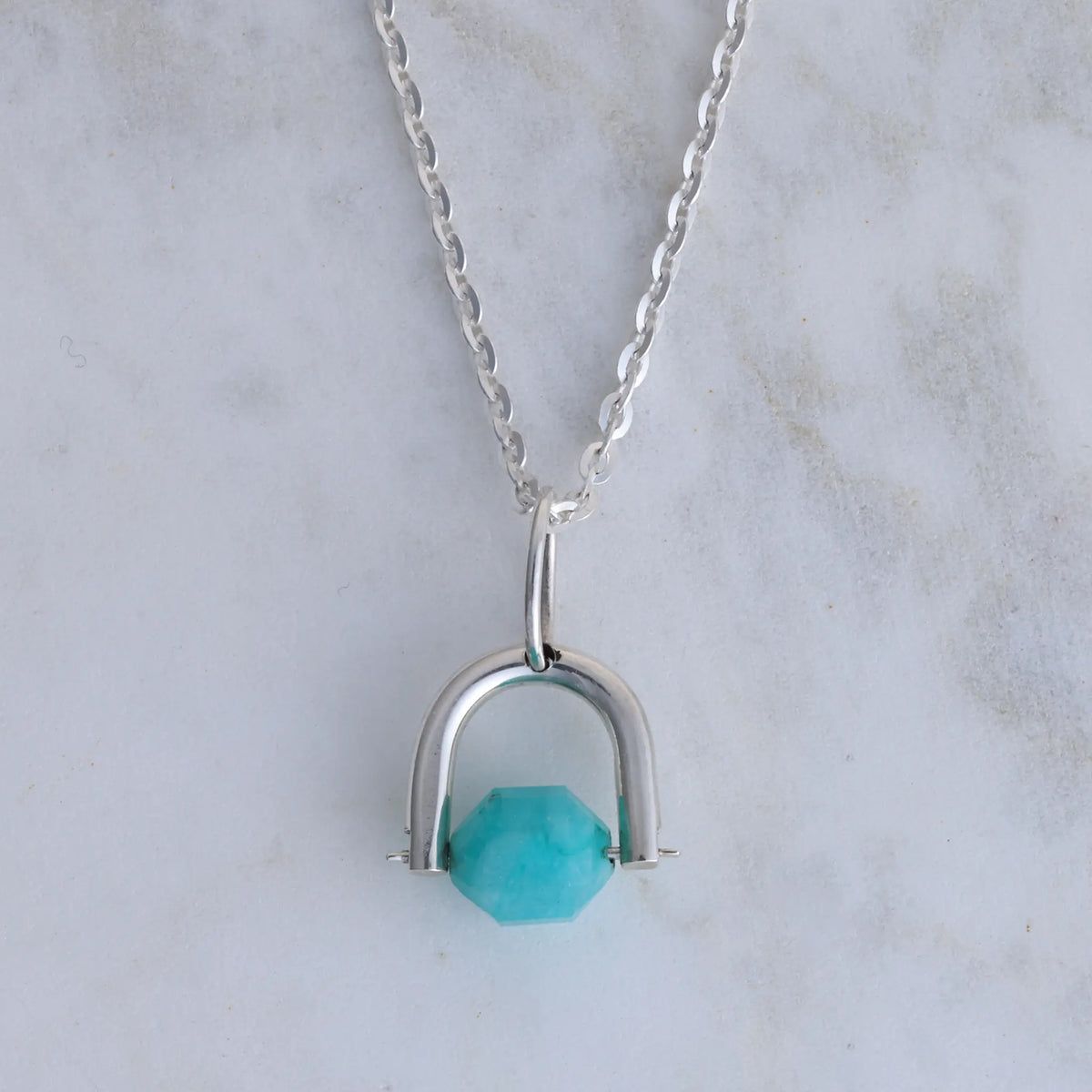 Silver necklace with a amazonite pendant on a marble background