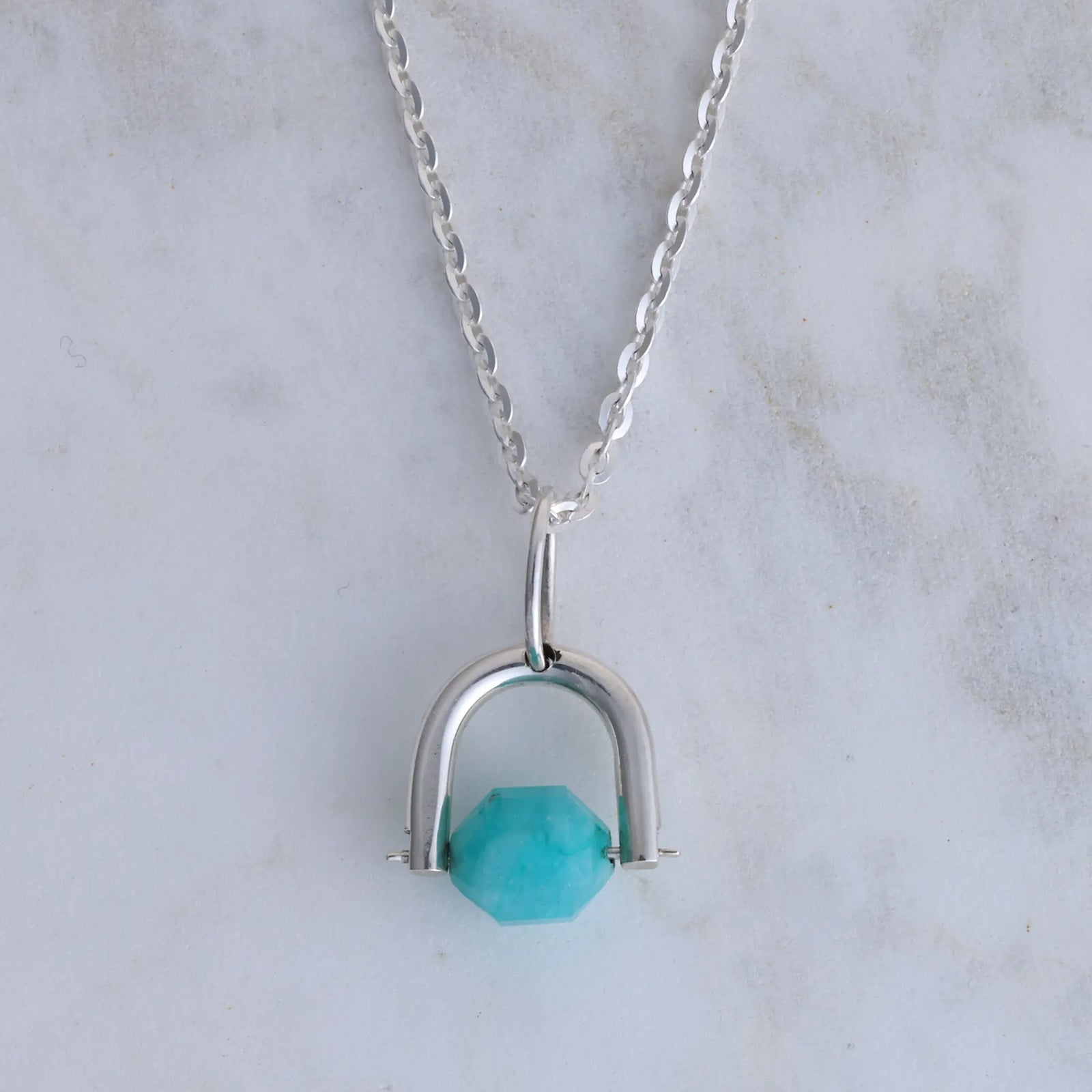 Silver necklace with amazonite pendant on a wooden surface