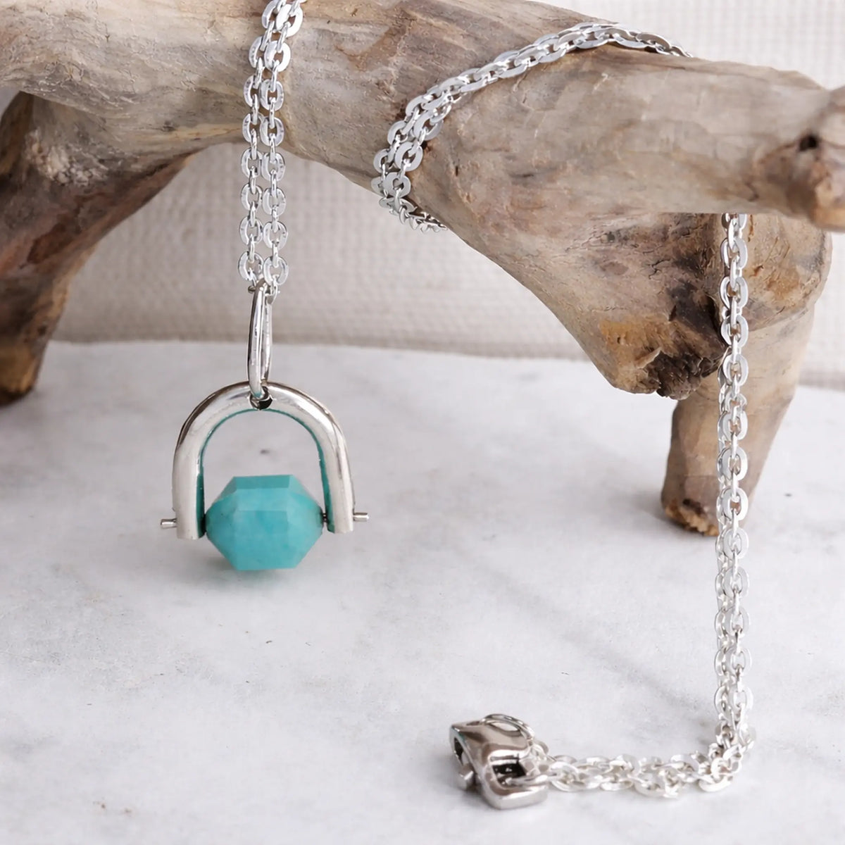 Silver necklace with amazonite pendant on a wooden surface