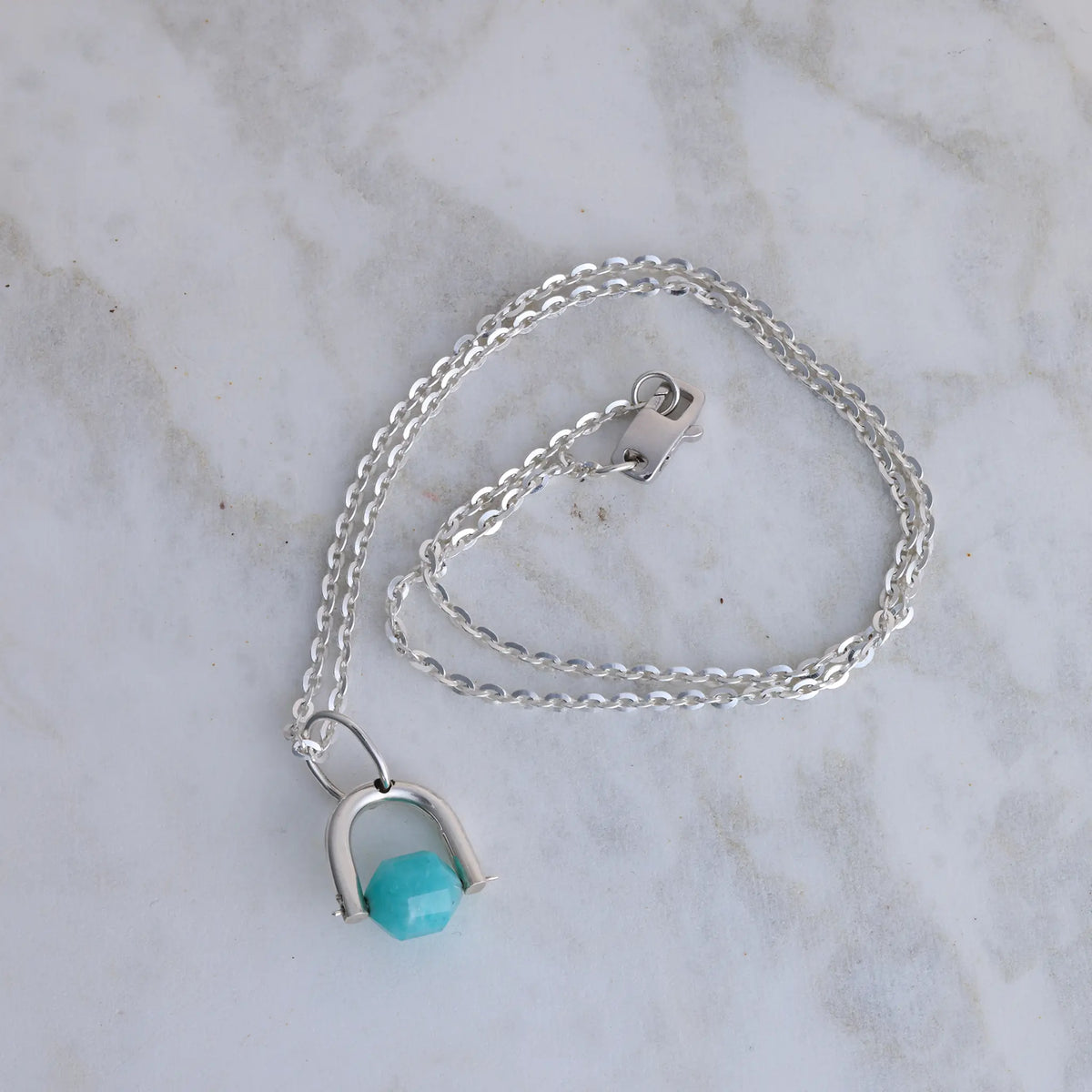 Silver necklace with a amazonite pendant on a marble surface