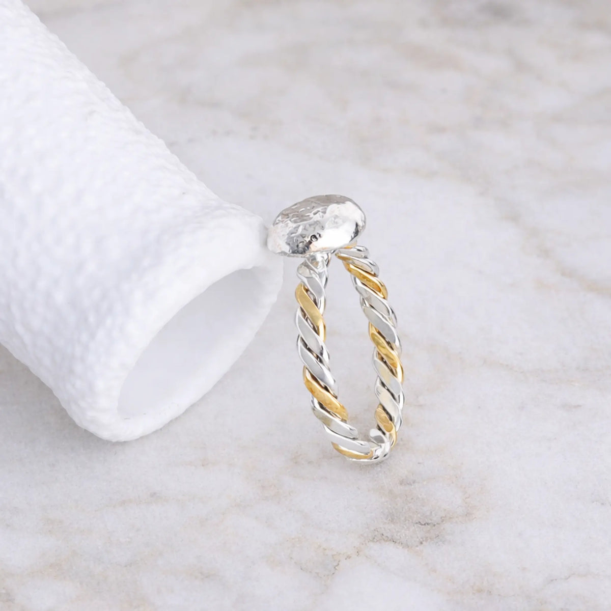 Silver and gold twisted ring on a marble surface