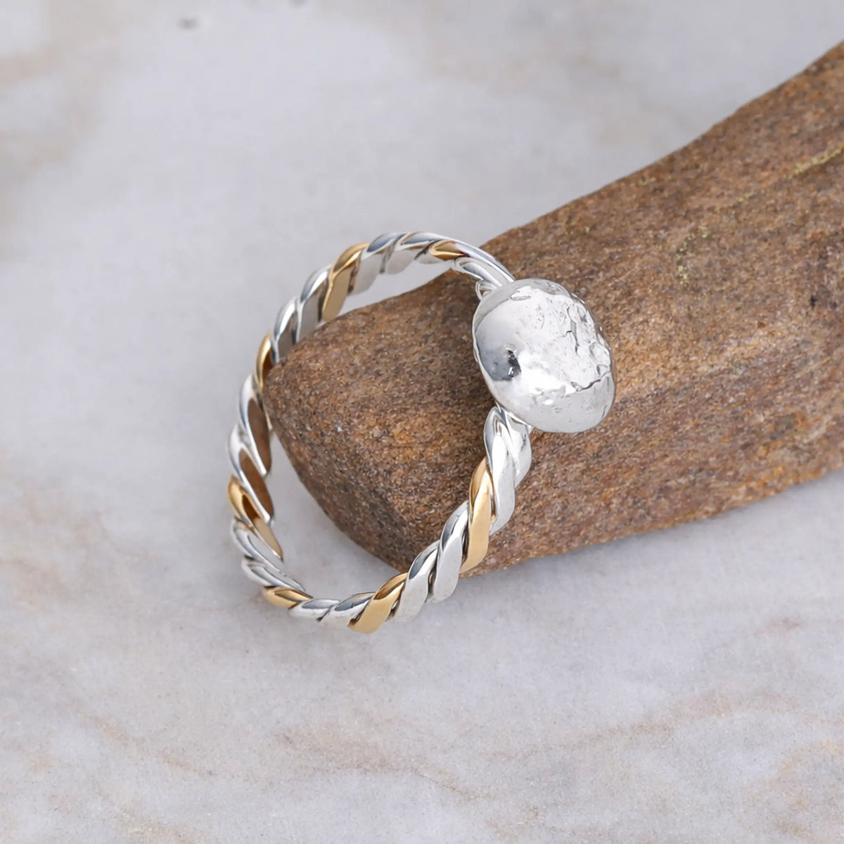 Silver and gold ring on a stone surface